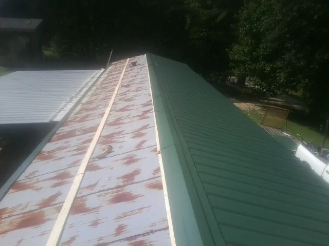 Old rusted panels beside newly installed green metal roofing — Wind Damage Roof Repair by Roofing Brothers in Sioux Falls