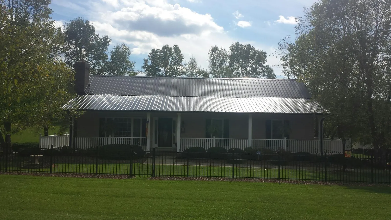 Gray metal roof on a brick ranch with a full width front porch — Gutter Guard Installation work by our crew in Sioux Falls