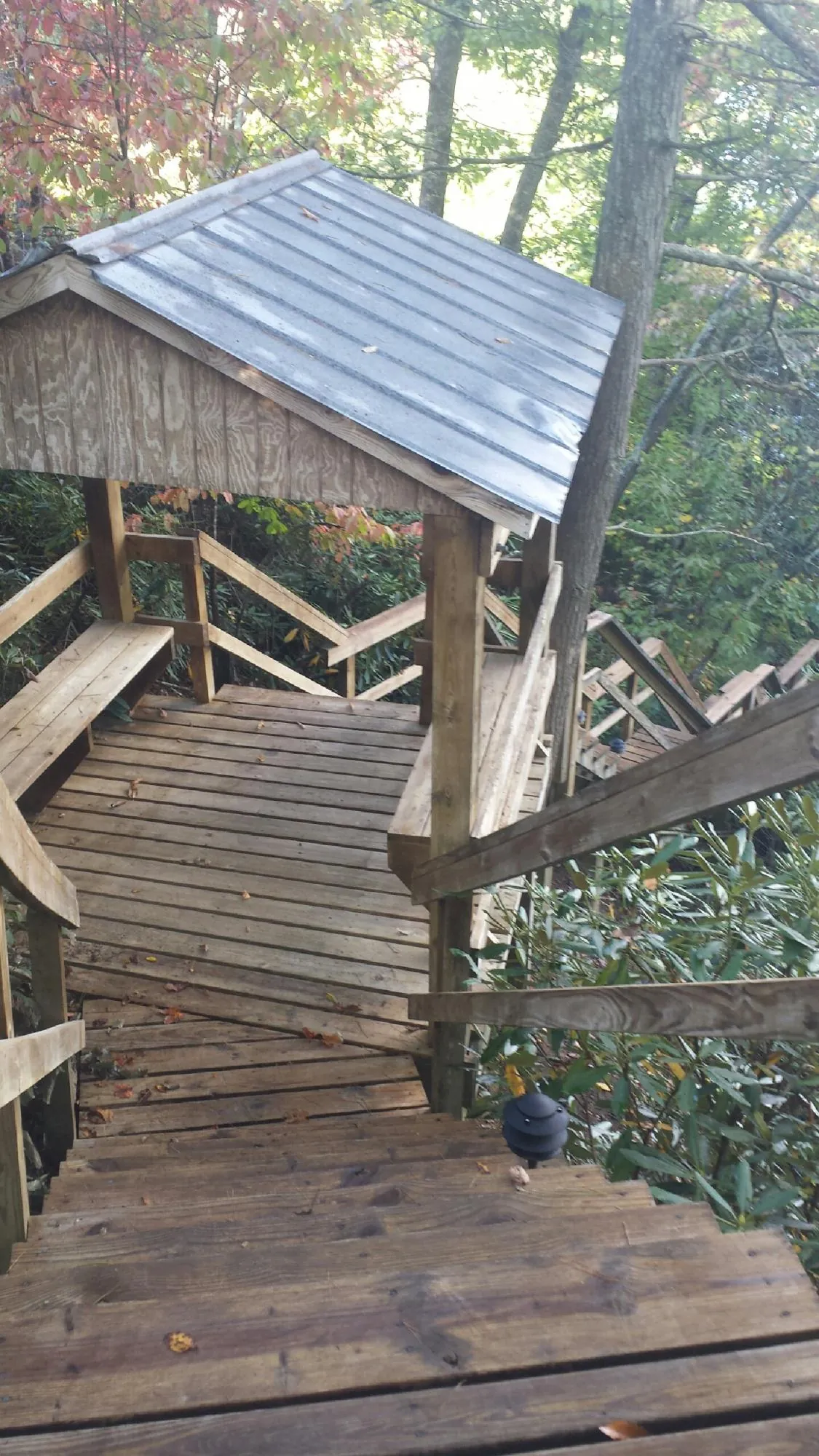 Metal roofed shelter over wooden steps on a wooded walkway — Skylight Repair & Installation work by our crew in Sioux Falls